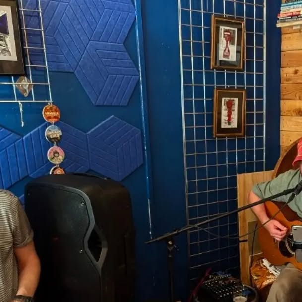 A live acoustic set inside the pub, against the blue wall with pump clips and local art pinned up