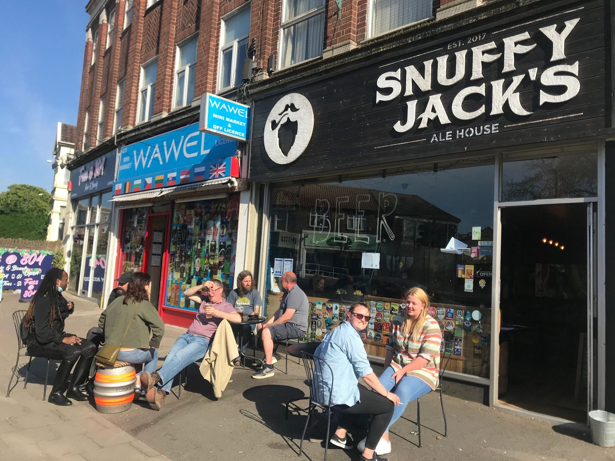 The black timber front of Snuffy Jack's Ale House on Fishponds Road on a sunny day, with people at tables on the pavement
